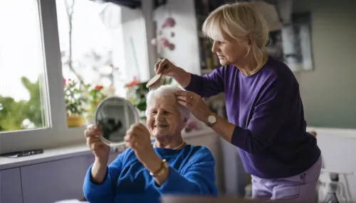 Frau kämmt Haare ihrer alten Mutter