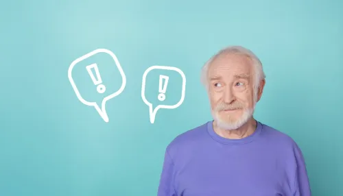 Älterer Mann auf einem türkis-farbenen Hintergrund der auf zwei Ausrufezeichen in Sprechblasen schaut