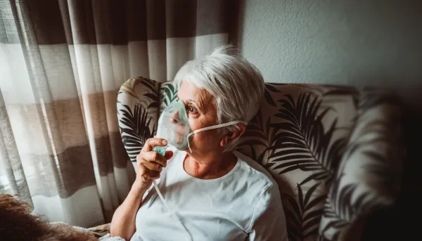 Seniorin trägt Sauerstoffmaske Sitzt Mit Hund Auf Stuhl Zu Hause