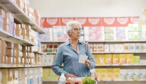 Verwirrte ältere Frau kauft Lebensmittel im Supermarkt ein