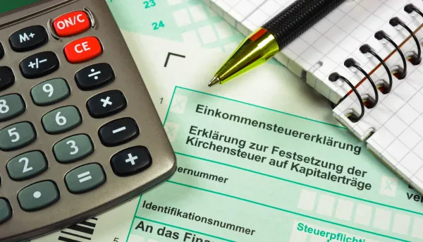 Einkommensteuer-Formular, Taschenrechner und Notizblock auf einem Schreibtisch