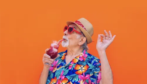 Lustiger und extravaganter älterer Mann, der auf farbigem Hintergrund posiert - Junger alter Mann in den sechziger Jahren, der Spaß hat und feiert