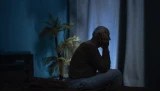 Silhouette eines alten Mannes, der an Schlaflosigkeit leidet und nachts schläfrig auf dem Bett sitzt.