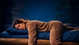 Frau schlafend auf einem Bett. Ein Arm und ein Bein hängen von der Bettkante.