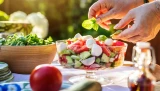 Frau garniert einen sommerlichen Salat mit einem Basilikumblatt
