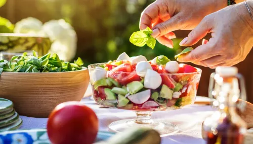 Frau garniert einen sommerlichen Salat mit einem Basilikumblatt
